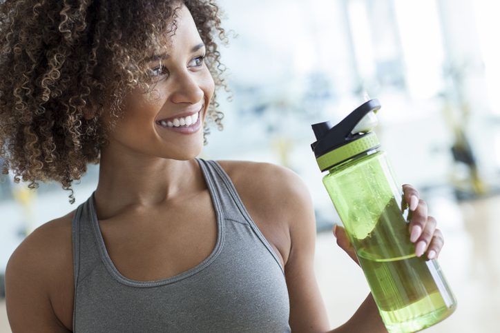 young woman holding a plastic bottle of water at the gym